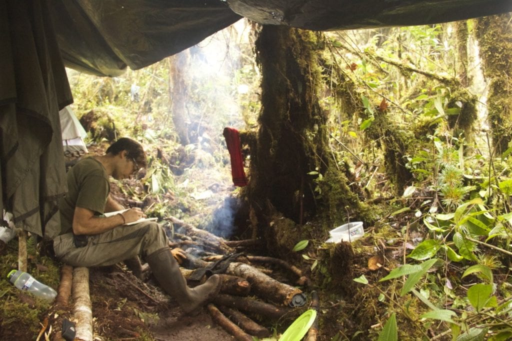 José Padial drying clothes and writing the expedition diary in front of the fire at Camp 03, 2550 m (ca. 8,400 ft). (Photo Santiago Castroviejo).