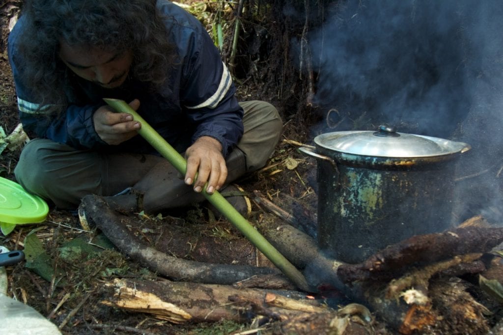The hyper-humid conditions at Camp 4 (2760 m, 9,055 ft) make lightning a fire a difficult task. Here, Giussepe Gagliardi tries a traditional technique consisting in blowing through a bamboo cane. (Photo Santiago Castroviejo).