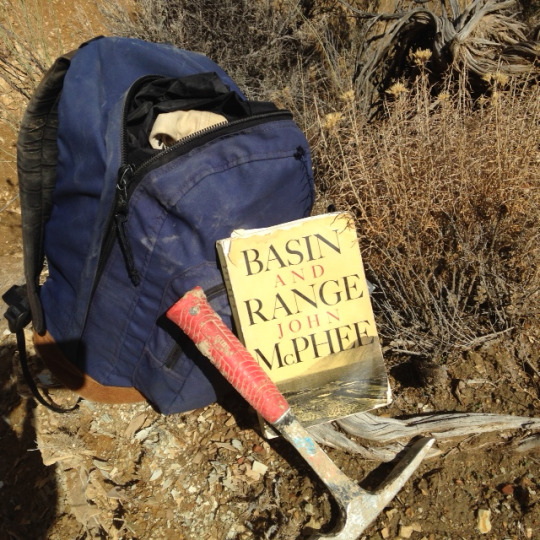 Backpack, book, and hammer sitting in the desert