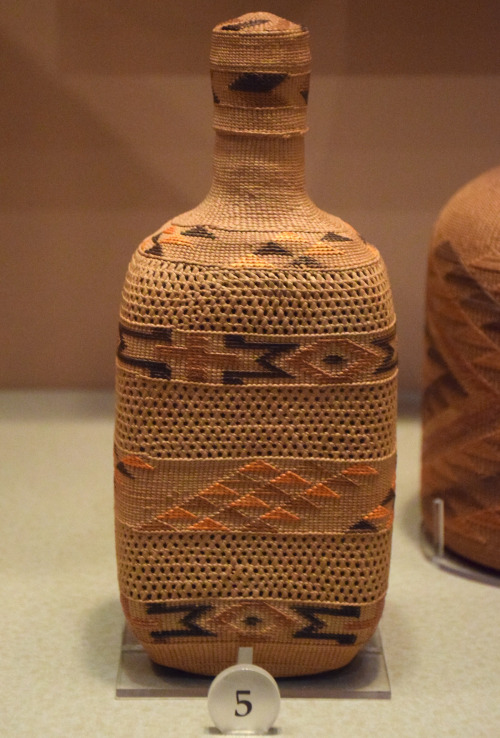 Glass bottle covered in a brow and orange woven wrap with a geometric pattern on it