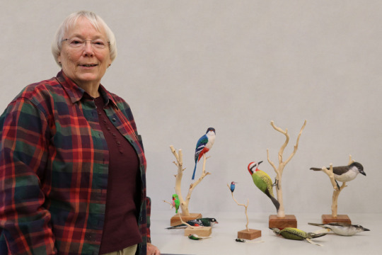 Susan standing in front of three wooden bird carvings