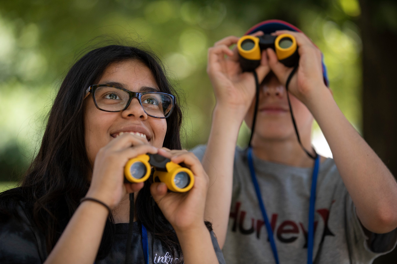 two children looking through binoculars