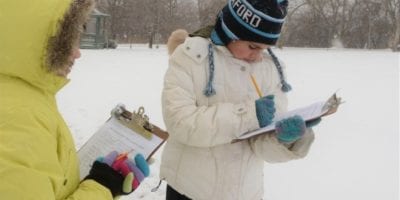 two people taking notes outside in winter