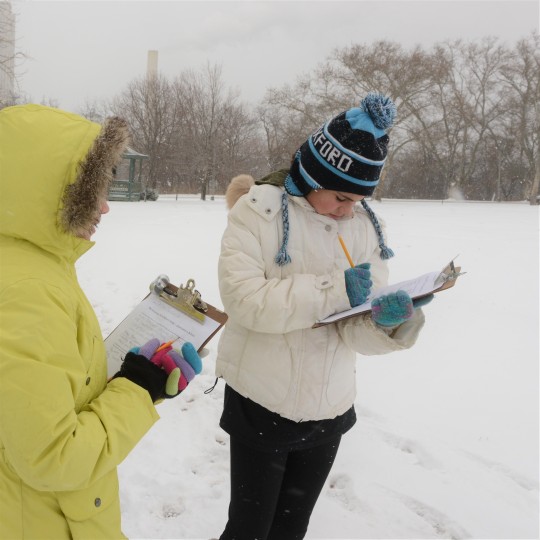 two people taking notes outside in winter