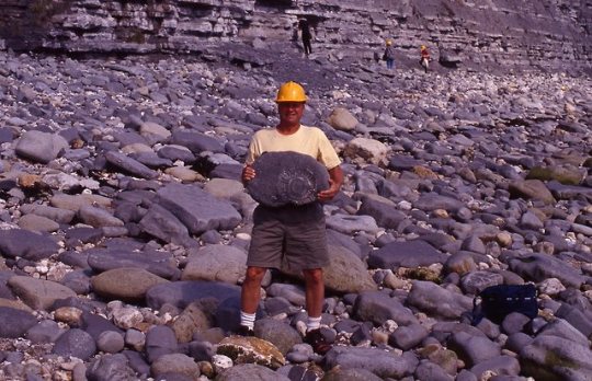 Albert Kollar holding a fossil among rocks