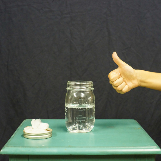 mason jar filled with water, mason jar lid with ice, and thumbs up