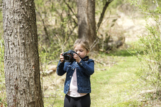 girl holding a camera in the woods