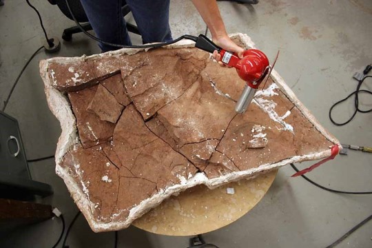 image of using a heat gun on a slab of rock in the process of fossil preparation