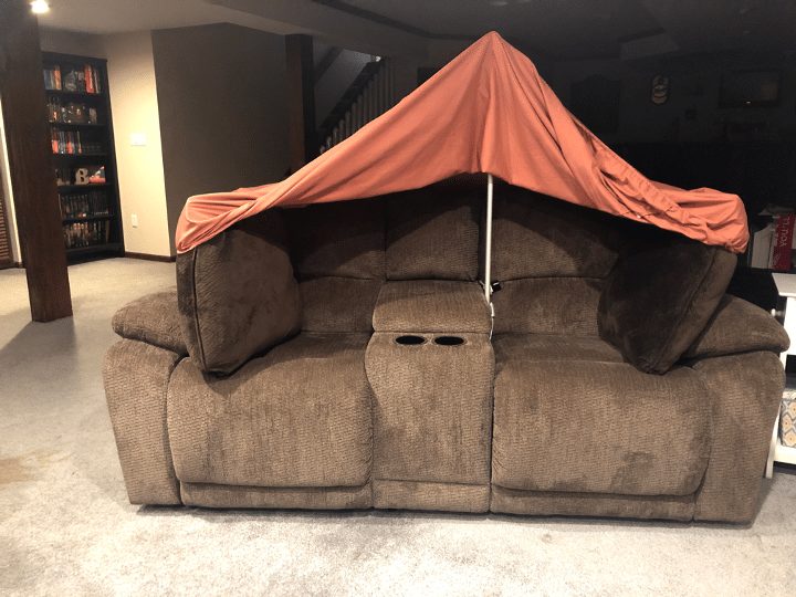 blanket supported by pole in center of couch