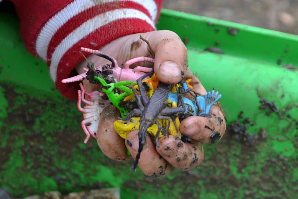 kid holding toys over dirt bin