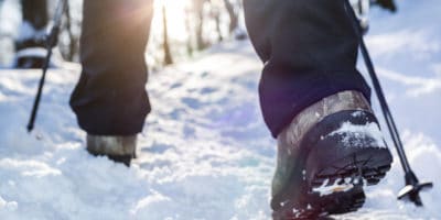 two feet walking in the snow with treking poles