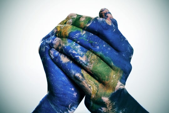 two hands clasped together and painted to look like the earth
