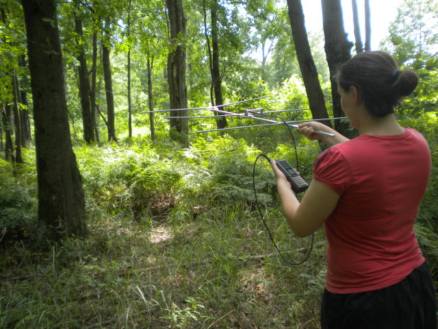 woman holding an antenna and receiver in the woods