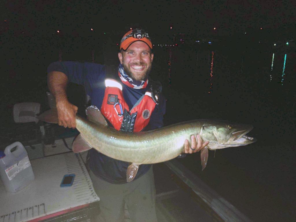 person holding a large fish at night
