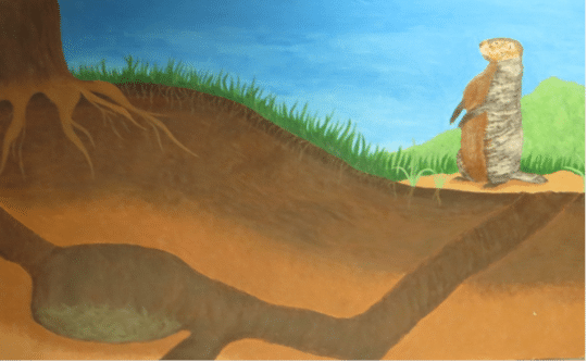 illustration of a groundhog standing near the entrance to a groundhog burrow