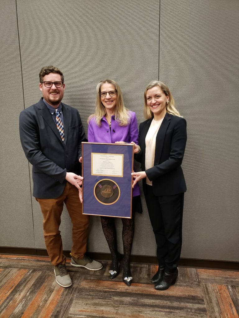 Three people holding the framed 2021 Carnegie Mineralogical Award
