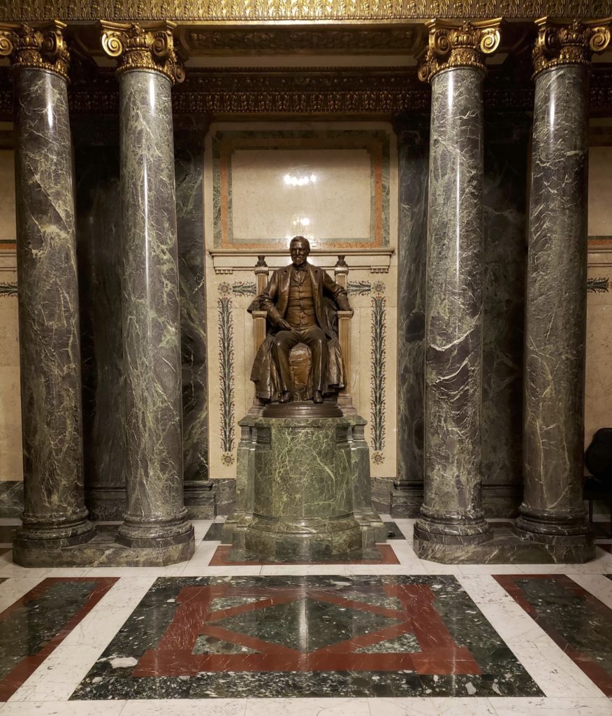 Sculpture of Andrew Carnegie in an ornate marble room. 