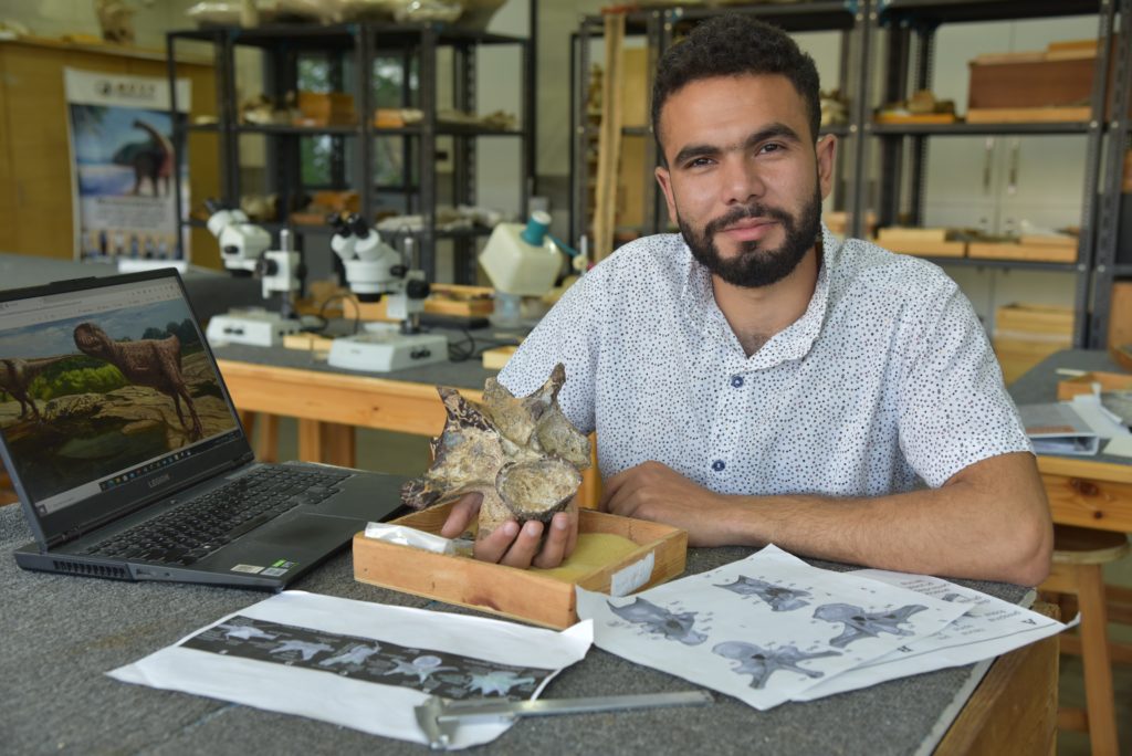 Person sitting at a desk holding a fossil