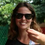 a person posing for the camera holding a gecko