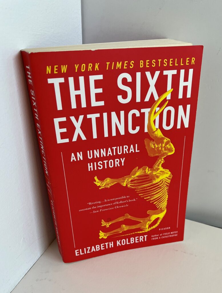 a paperback copy of the book "The Sixth Extinction"