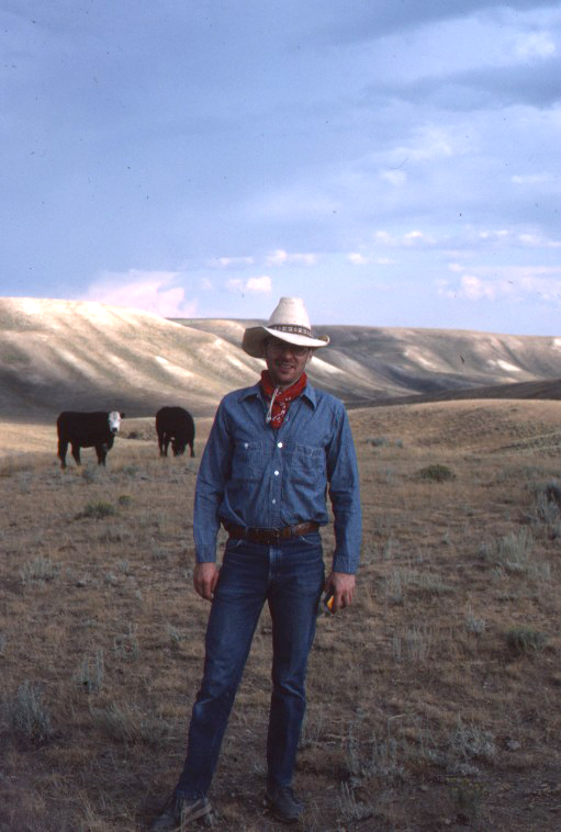 Pat McShea outdoors in a field with cows and hills in the background