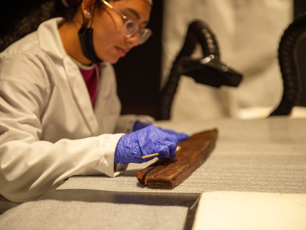 conservator cleaning ancient wood with a q-tip