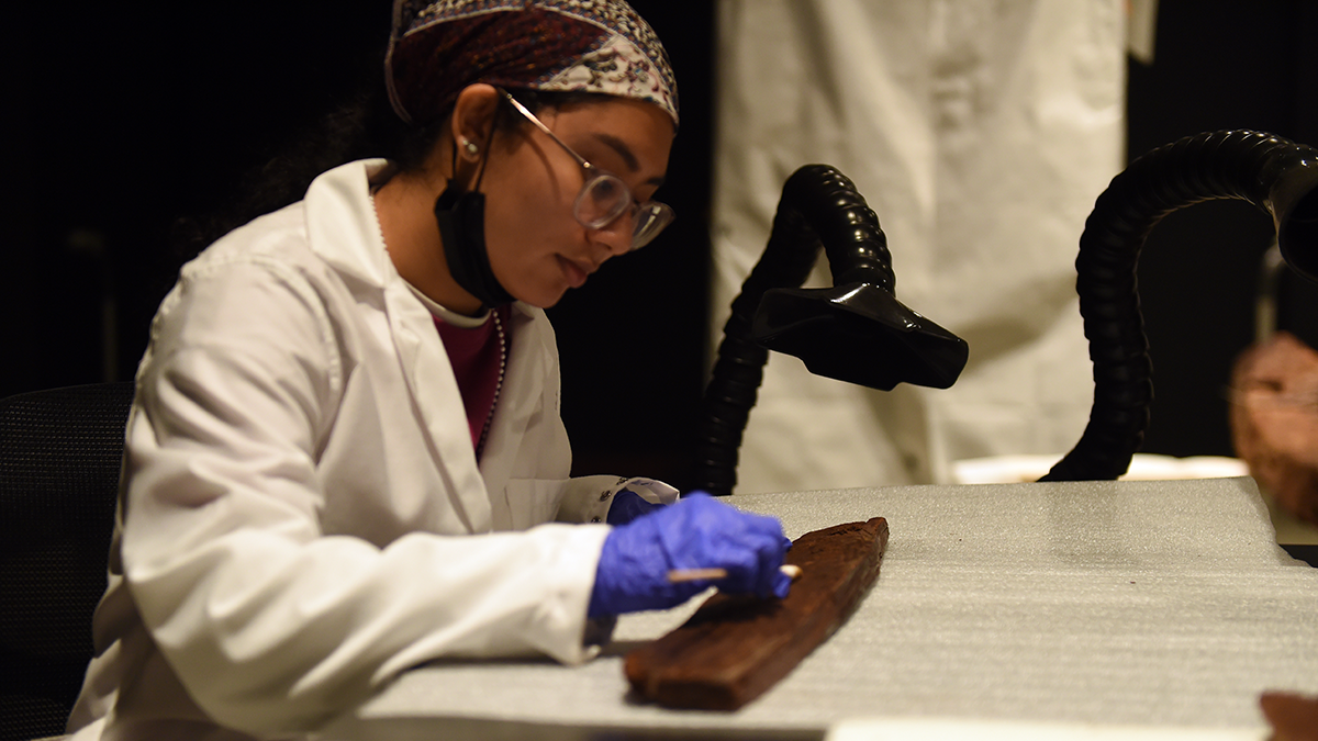 A conservator works on an artifact