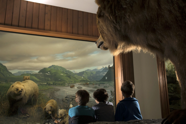 Three children look at a bear exhibit